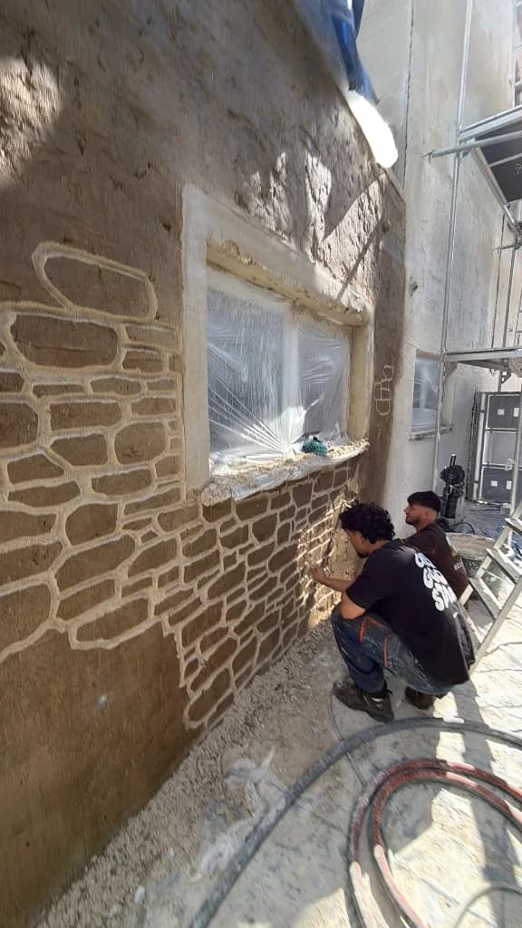 Artisans Bel-Pierre traçant les pierres dans l'enduit d'une façade